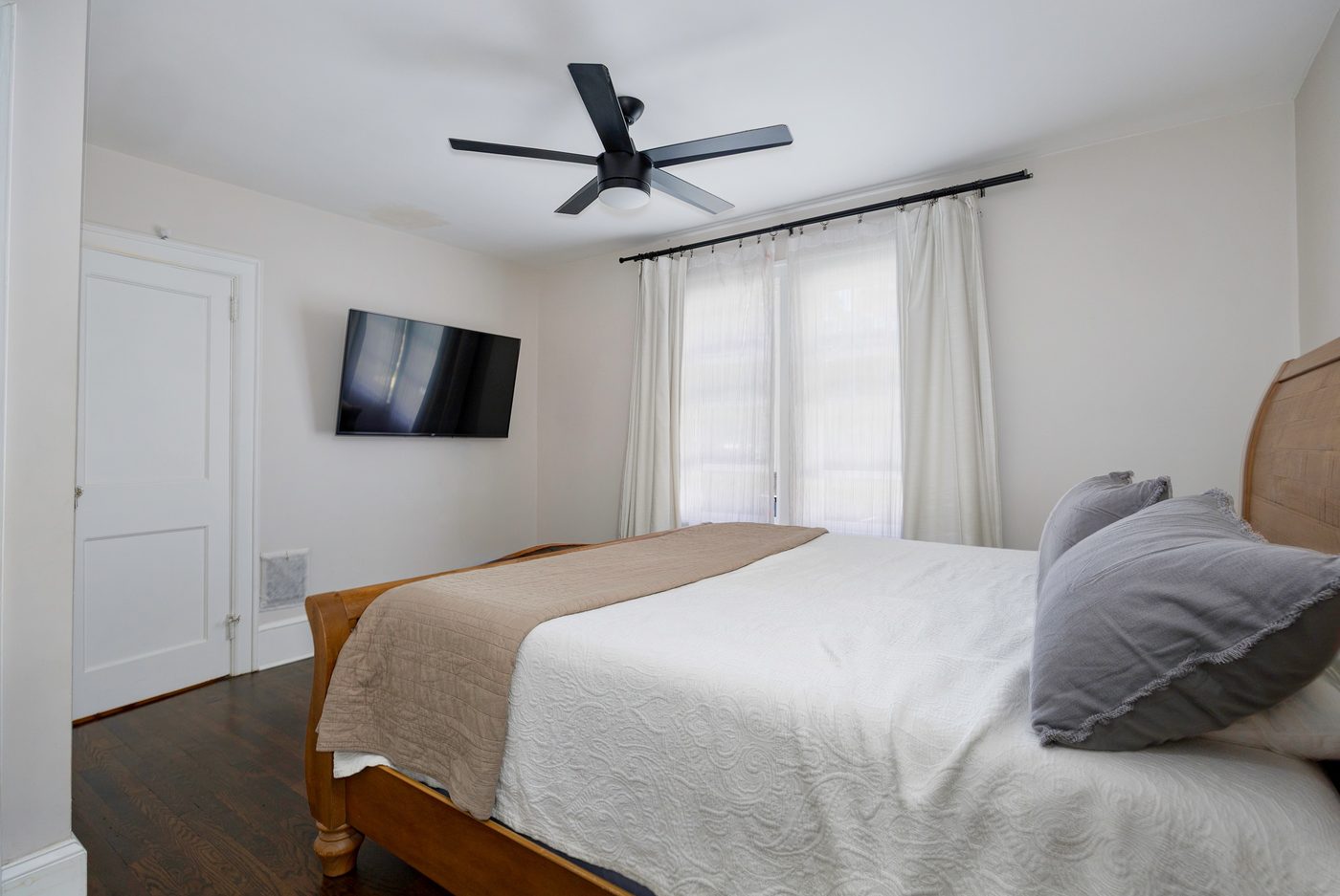 Ceiling fan installed in a bedroom alongside a wall-mounted TV