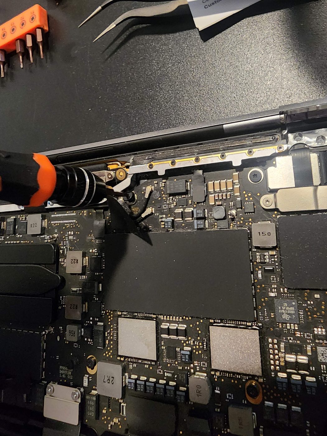 Laptop opened on the bench for a screen replacement, motherboard and tools visible
